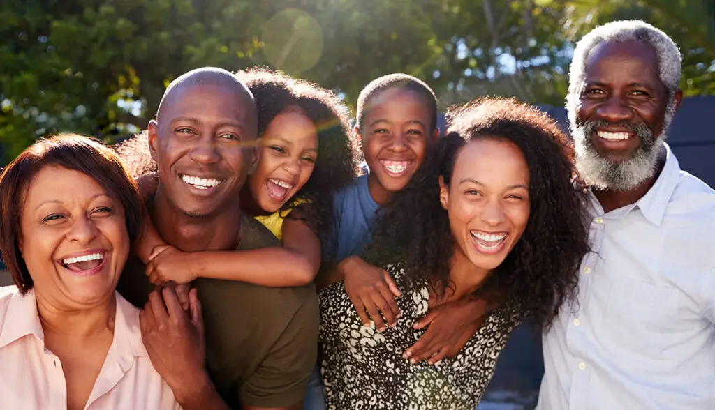 Outdoor Portrait Of Multi-Generation Family In Garden At Home Against Flaring Sun